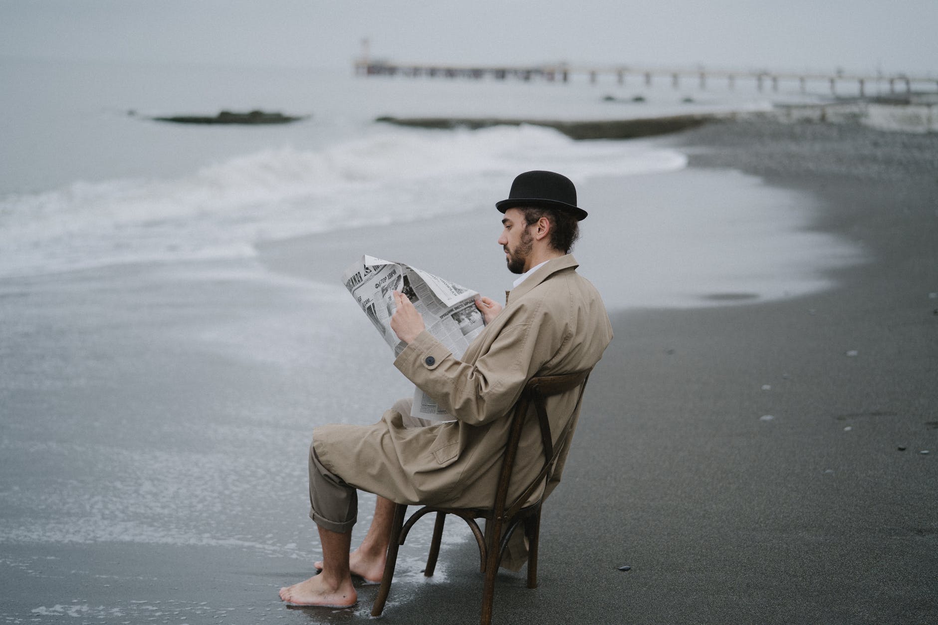 a man reading a newspaper on a beach